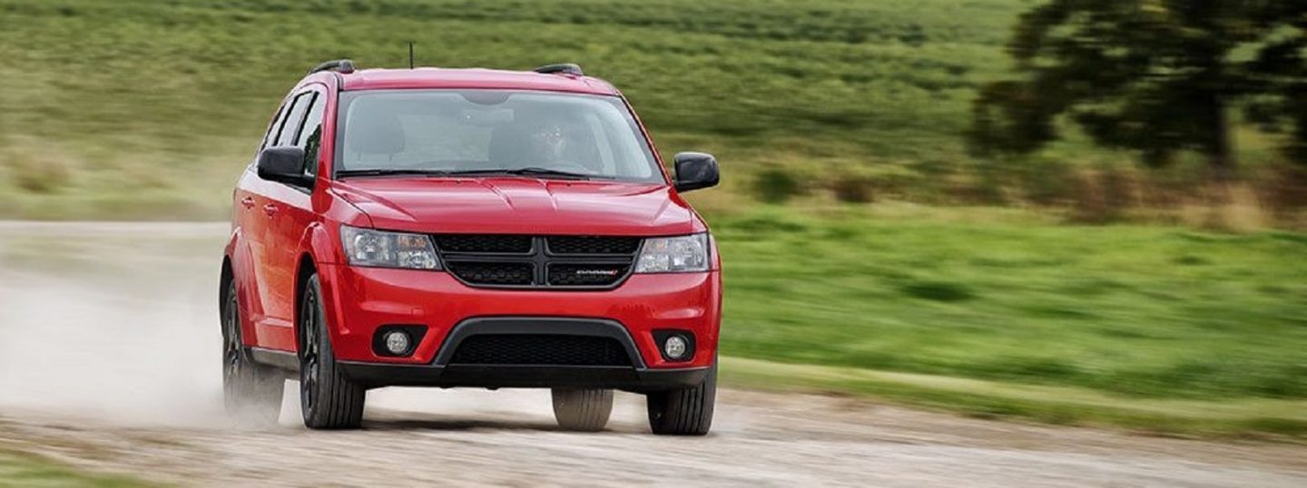 Dust flying from the wheels of the 2019 Dodge Journey as it is driven on a country road.