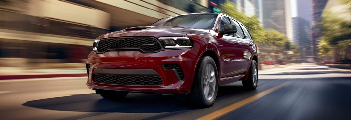 A red 2025 Dodge Durango R/T traveling on a city street with the background blurred.