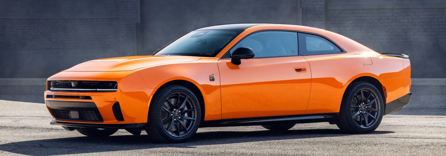 A driver-side angled profile of an orange 2026 Dodge Charger Scat Pack.