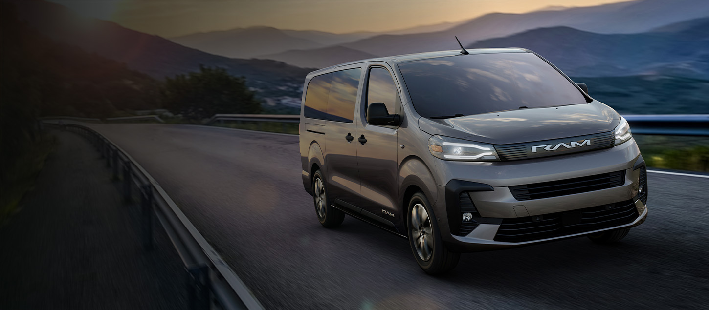 A gray 2027 Ram ProMaster City SLT Passenger Van traveling down a highway at sunset.