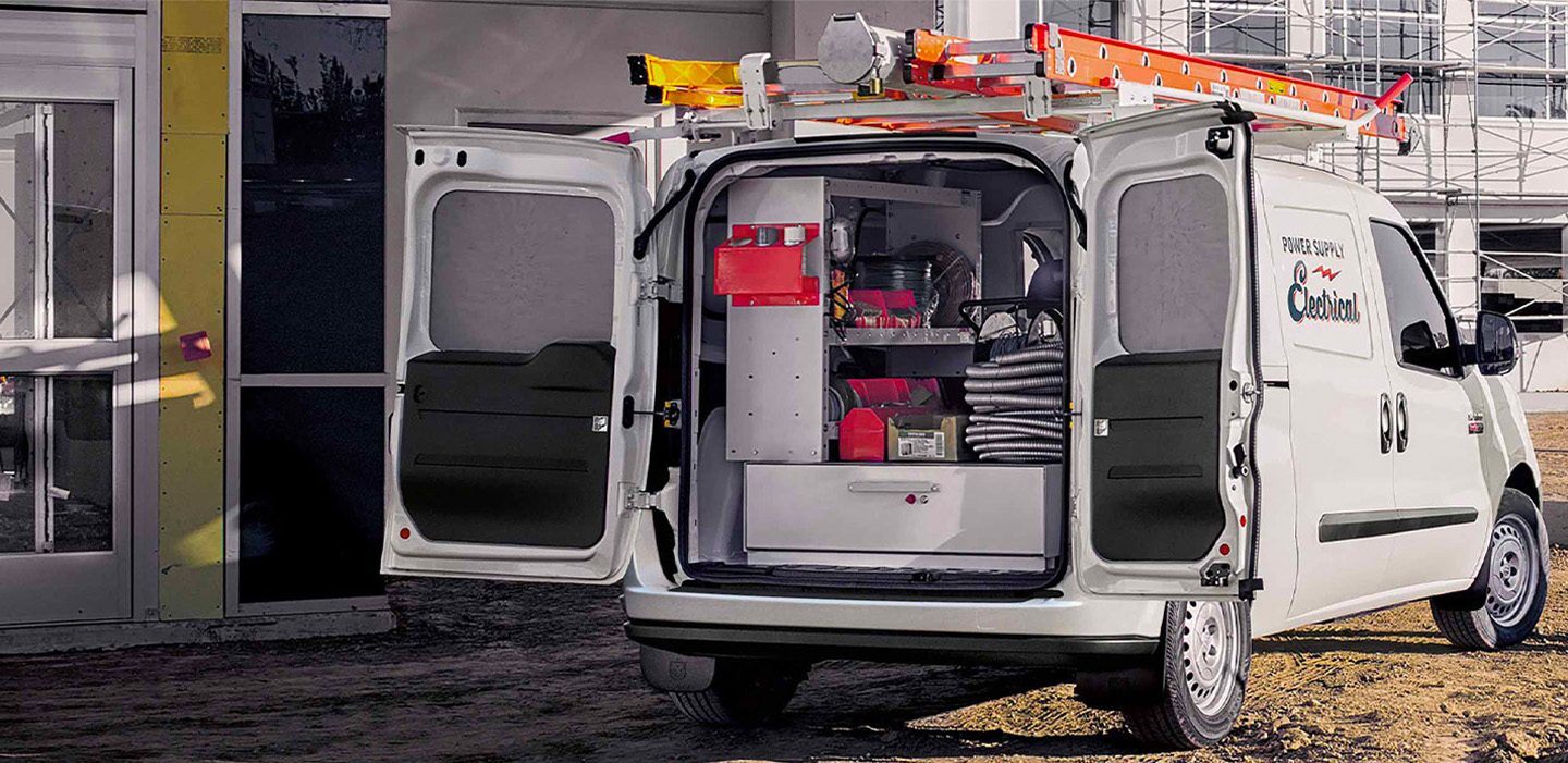 The 2022 Ram ProMaster City with its rear doors open to reveal shelf and drawer upfits in the cargo area holding electrical equipment.