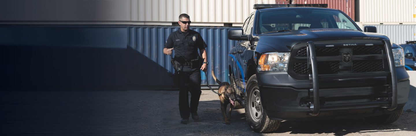 A police officer walking with a German Shepherd dog beside a 2022 Ram 1500 Classic Special Service.