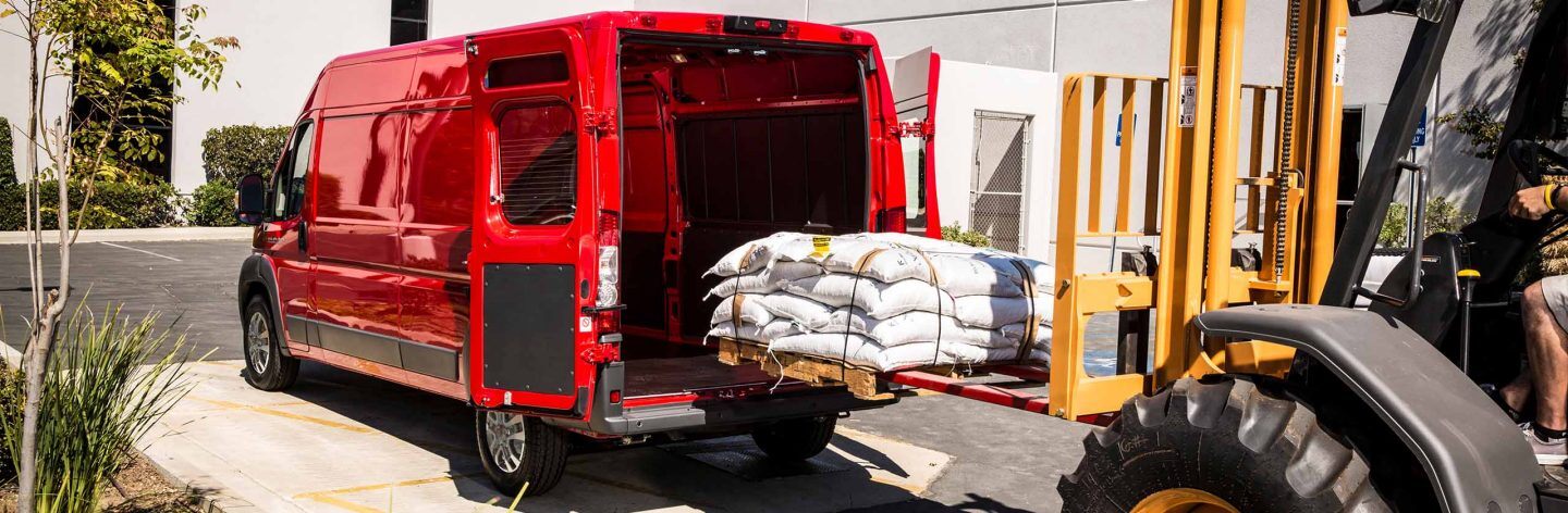 A forklift loading a pallet stacked with sacks into the rear of a 2023 Ram ProMaster 2500 Cargo Van.