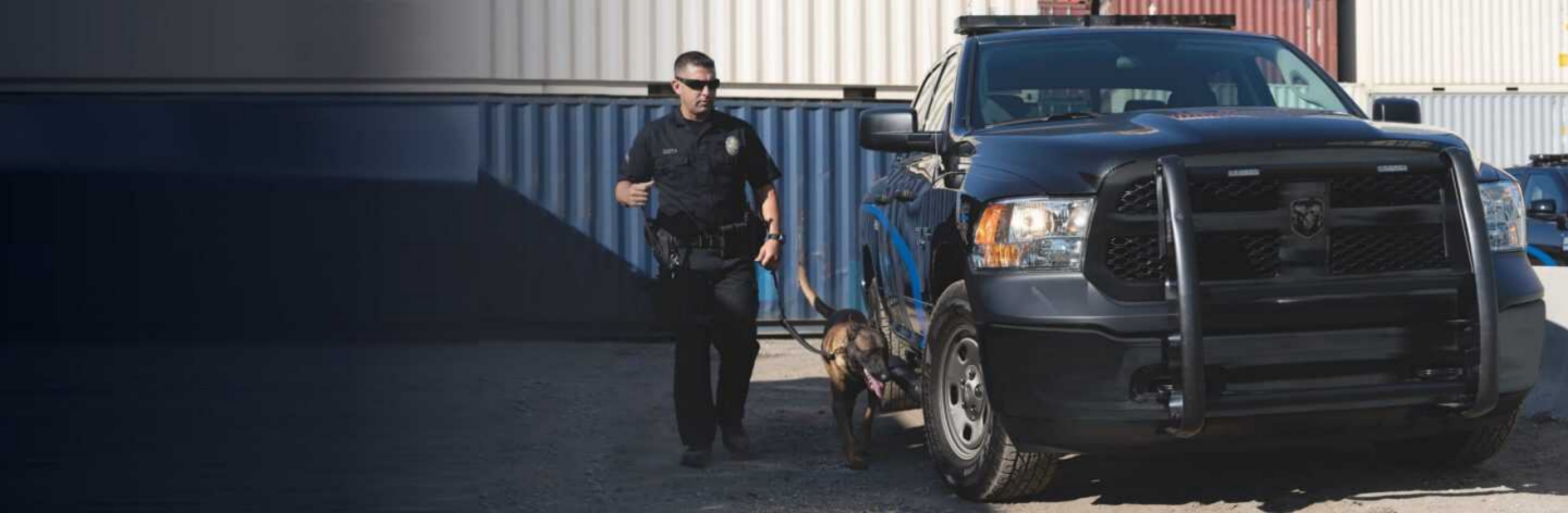 A 2023 Ram 1500 Classic Special Service parked next to an industrial building with a police officer and K-9 officer nearby.