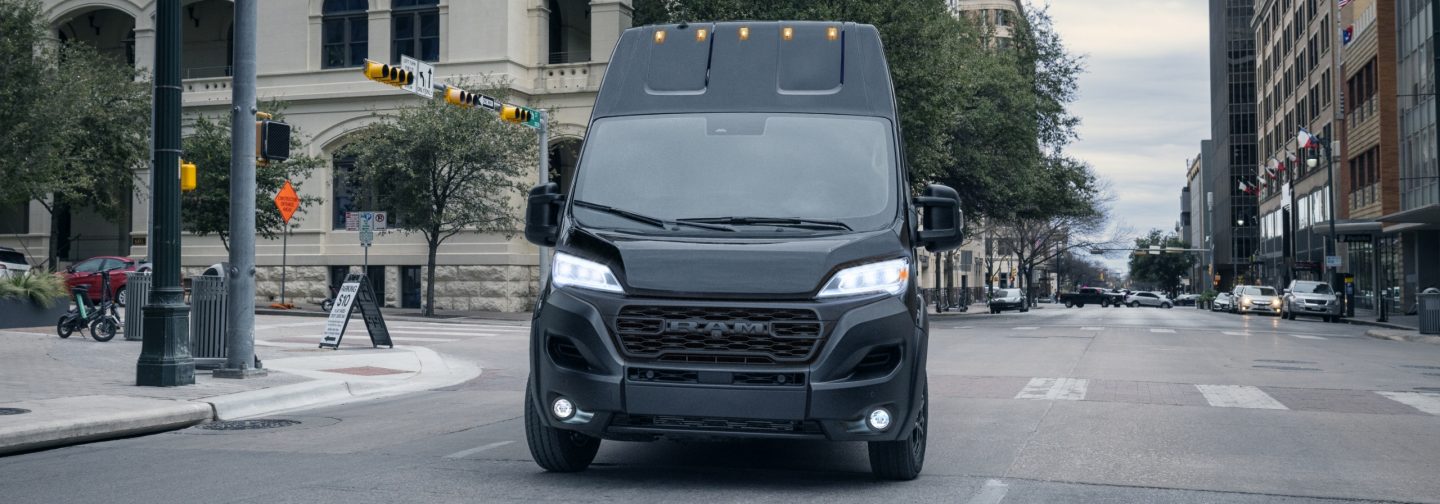 A black 2025 Ram ProMaster 3500 SLT Plus Cargo Van Super High Roof with Black Appearance Package, turning at an intersection.