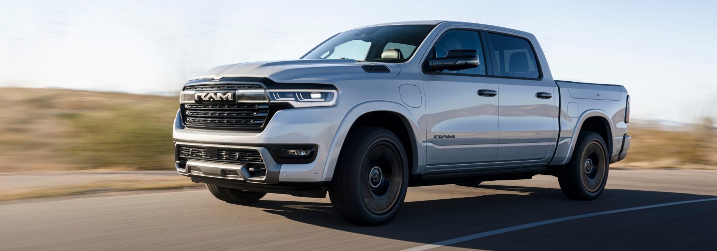 A driver-side angle of a silver 2025 Ram 1500 Ramcharger Limited 4x4 Crew Cab, being driven on the highway.