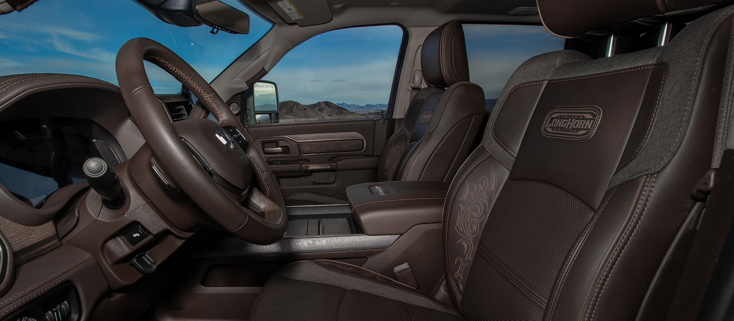 The black leather-trimmed front seats in a 2027 Ram 2500 Heavy Duty Limited Longhorn Crew Cab pickup truck, shot from the driver side.