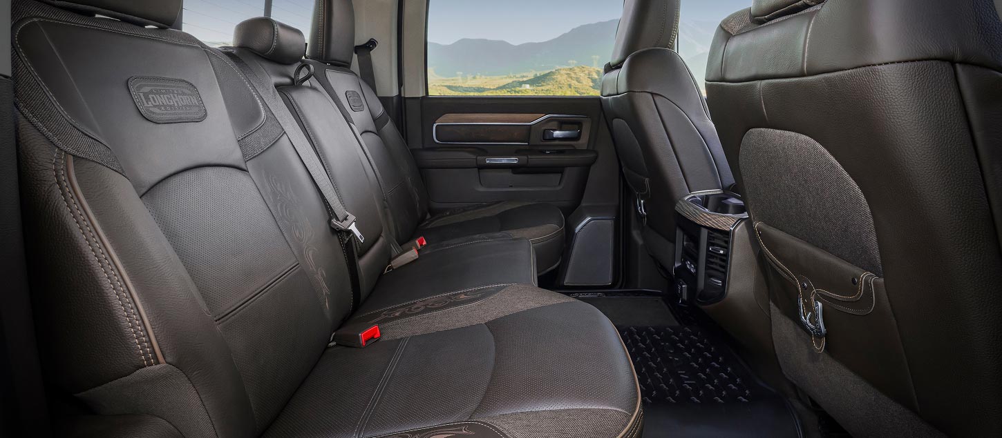The rear seats in the 2027 Ram 3500 Heavy Duty Limited Longhorn 4x4 Crew Cab pickup truck with an embroidered Limited Longhorn Edition logo on them. Shot from the passenger side.