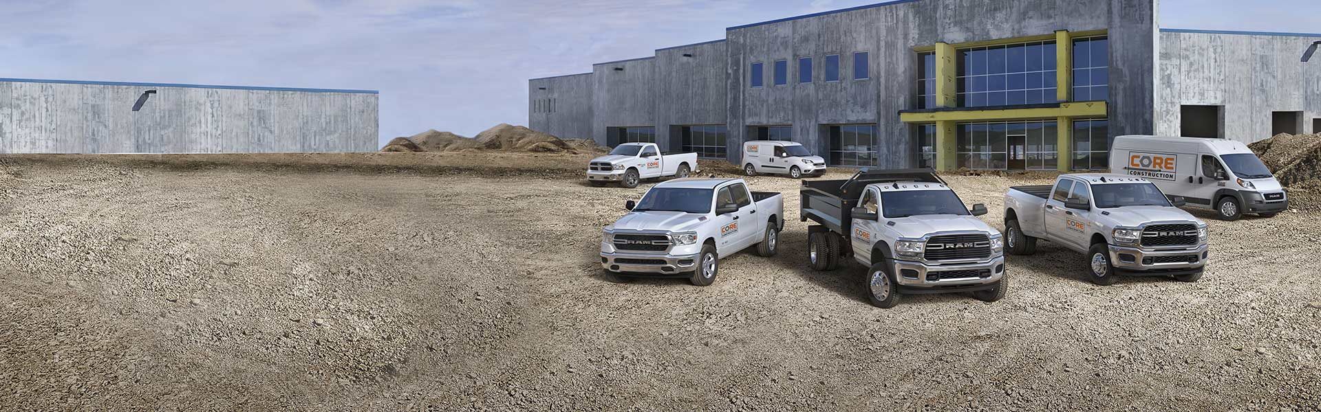 Six Ram vehicles including the Ram ProMaster City, Ram 1500 Classic, Ram 1500, Ram Chassis Cab, Ram 3500, and Ram ProMaster parked side by side at a construction site.
